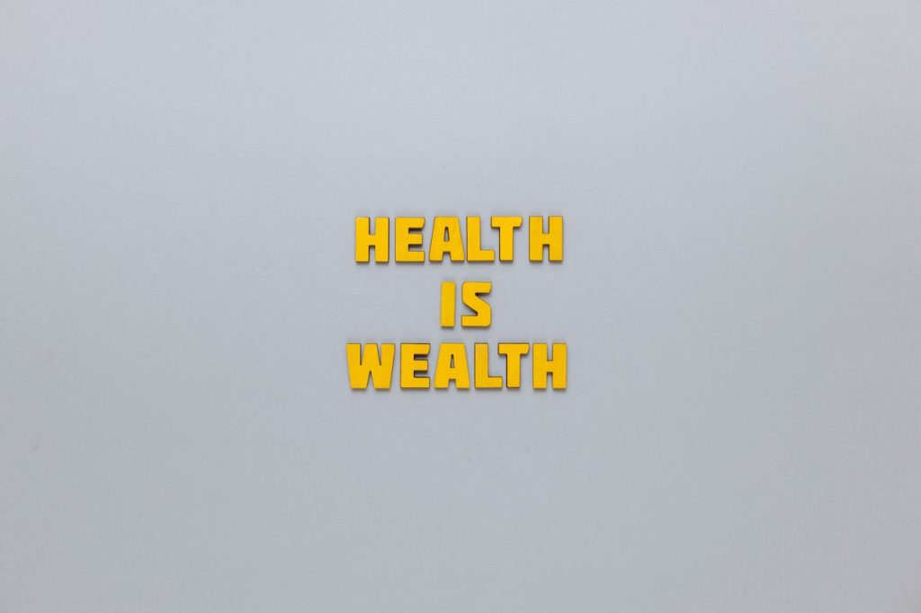 Inspirational phrase 'Health is Wealth' in bold yellow letters on a neutral gray background.
